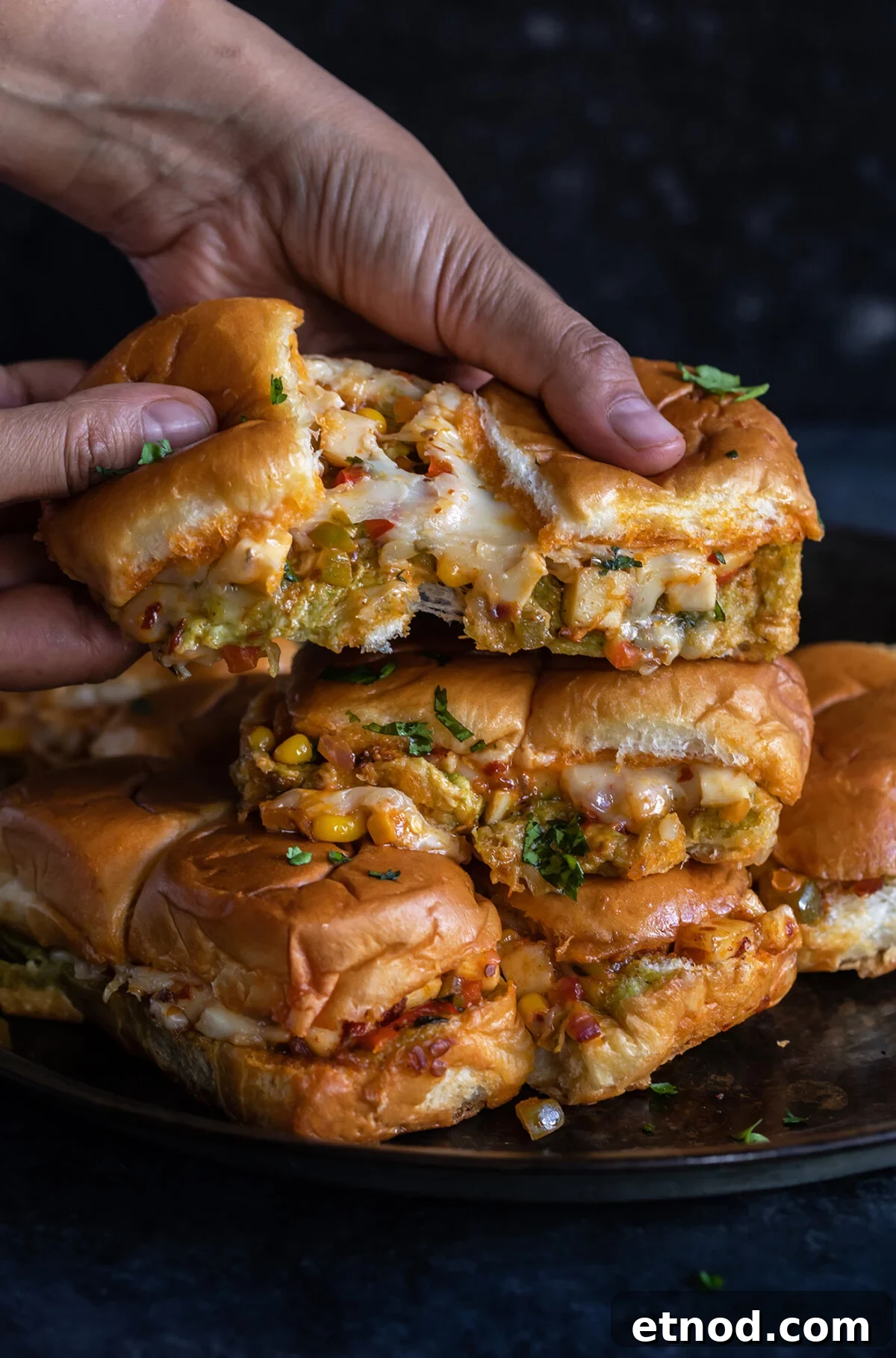 pair of hands pulling sliders apart to show the cheese pull