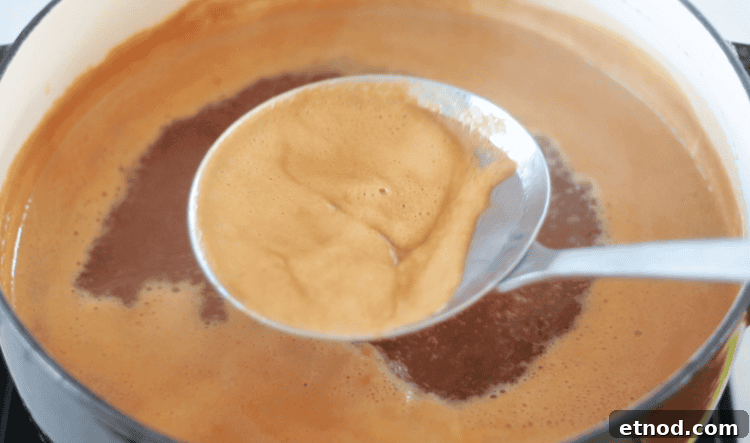 Boiled Apple Cider Syrup: Step-by-Step Recipe with Video 11 strainer skimming foam off of cider in pot