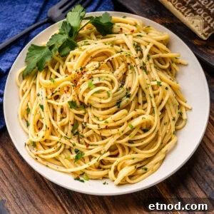 Linguine aglio e olio in white plate with parsley garnish.