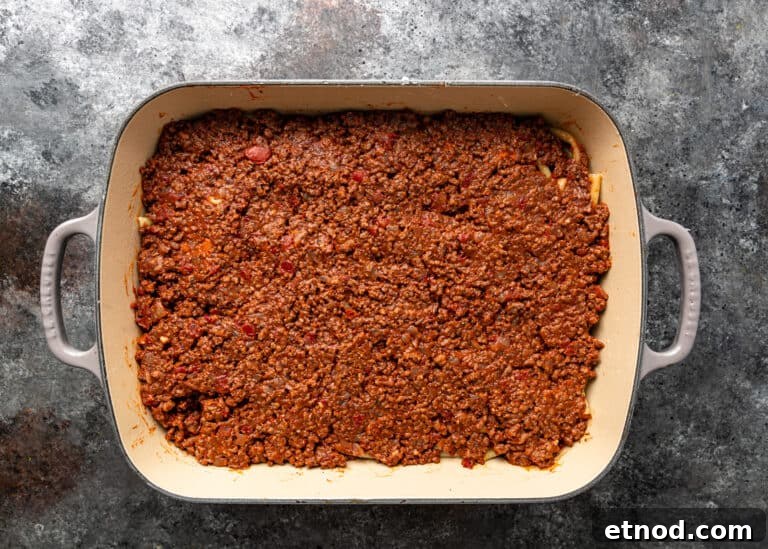 Authentic Greek Pastitsio Recipe: Classic Baked Pasta with Bechamel 11 overhead process shot: layer of meat sauce in casserole dish for pasticcio