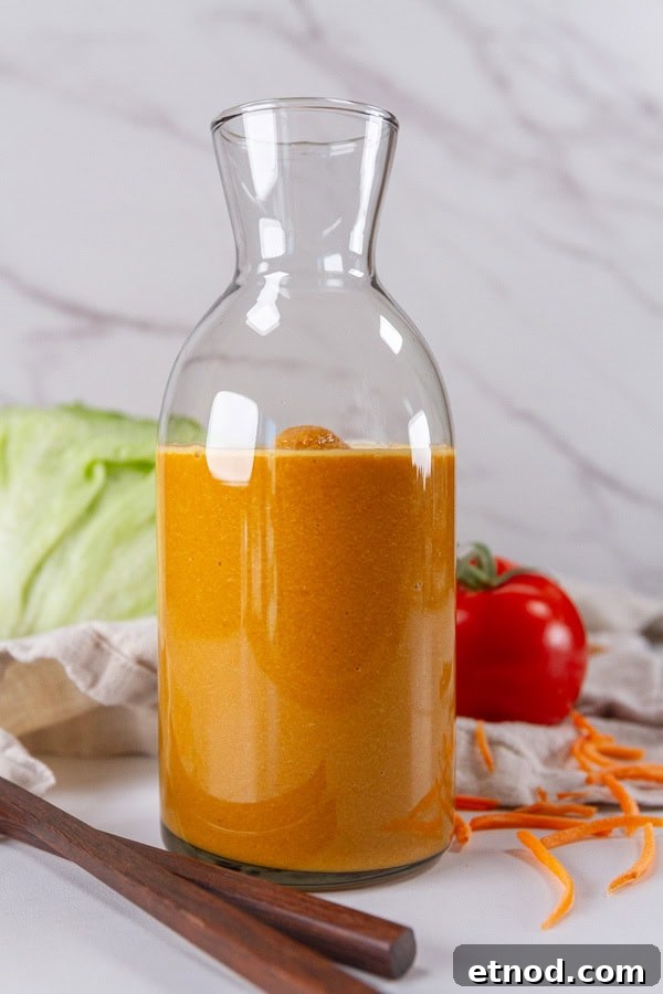 a bottle of salad dressing with chopsticks, a head of lettuce, and a tomato around it.