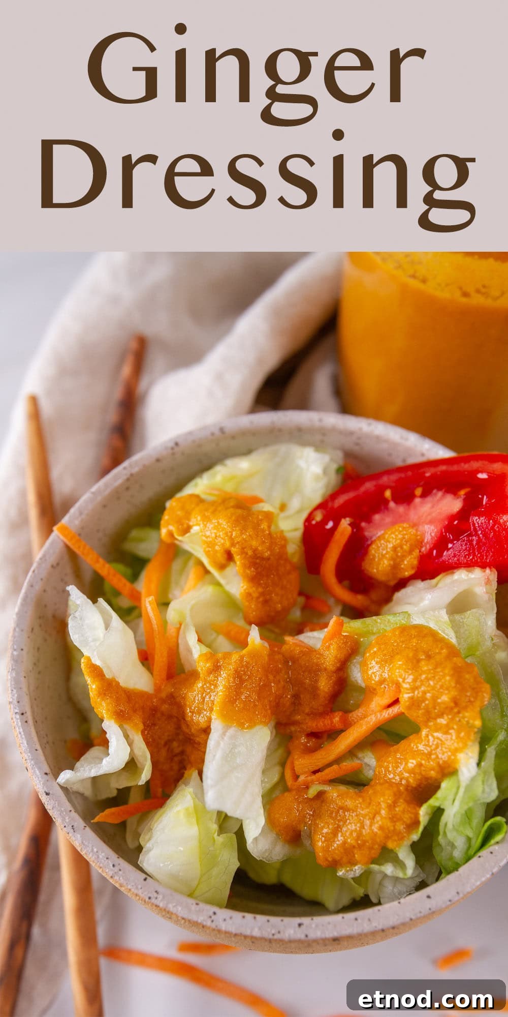 a salad in a small bowl topped with orange dressing and chopsticks next to the bowl.