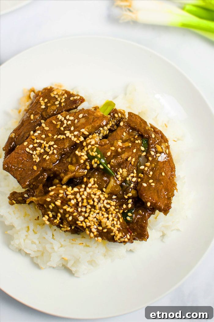 Instant Pot Mongolian Beef Recipe: Tender Beef in Sweet Garlic Sauce 3 Overhead Shot of Easy Homemade Mongolian Beef With Mongolian Sauce and Rice in White Plate