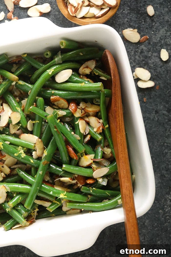 Green Beans Almondine is a fresh, buttery holiday side made with blanched green beans, a delicious slivered almond topping, and fresh lemon zest! green beans in casserole dish