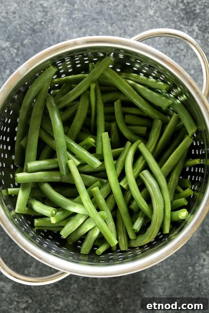 This green beans almondine recipe starts off by blanching fresh green beans and is finished with a delicious and buttery almond topping! green beans in strainer
