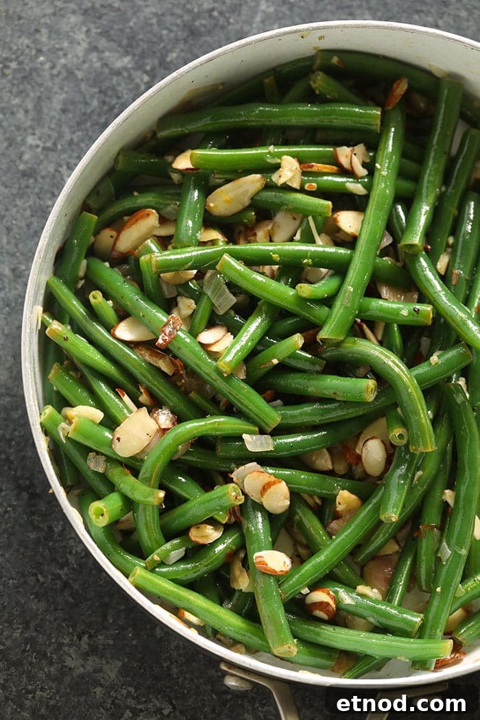 Our green beans almondine recipe is crunchy, buttery, and has a hint of lemon! green beans almondine in pan