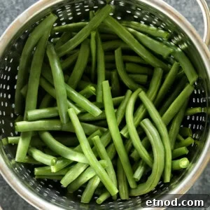 Green Bean Almondine Recipe: Sautéed Green Beans with Almonds 3 Green beans in a colander, served almondine-style.