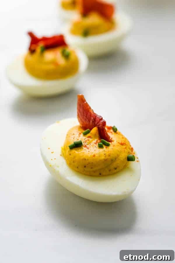 Southern-Style Deviled Eggs Recipe: Tangy Classic Appetizer 9 Healthy deviled egg with a small slice of country ham and chives.