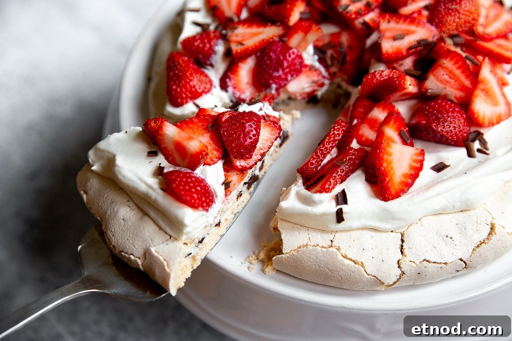 Close up of a slice of pavlova with dark chocolate, topped with whipped cream and strawberries.