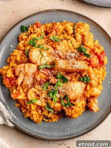 Seafood risotto topped with chopped basil on a plate.