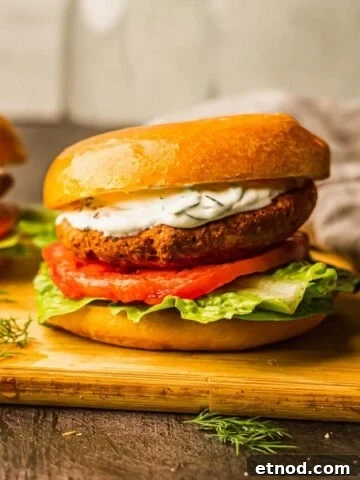 Salmon burgers with yogurt sauce on a cutting board.
