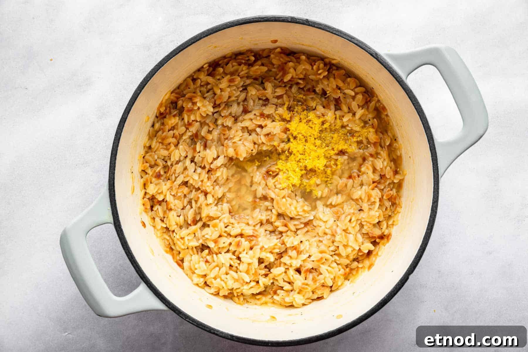 Creamy Lemon Orzo with Parmesan and Fresh Herbs 7 Lemon zest on top of pasta in a white pot.