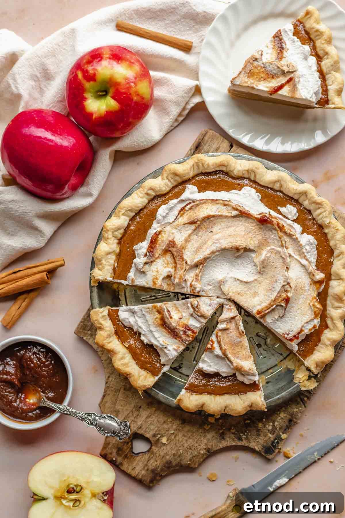 Apple butter pie with a slice removed and apples and apple butter on the side.
