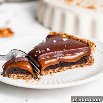 A fork cuts into a piece of caramel tart on a plate.