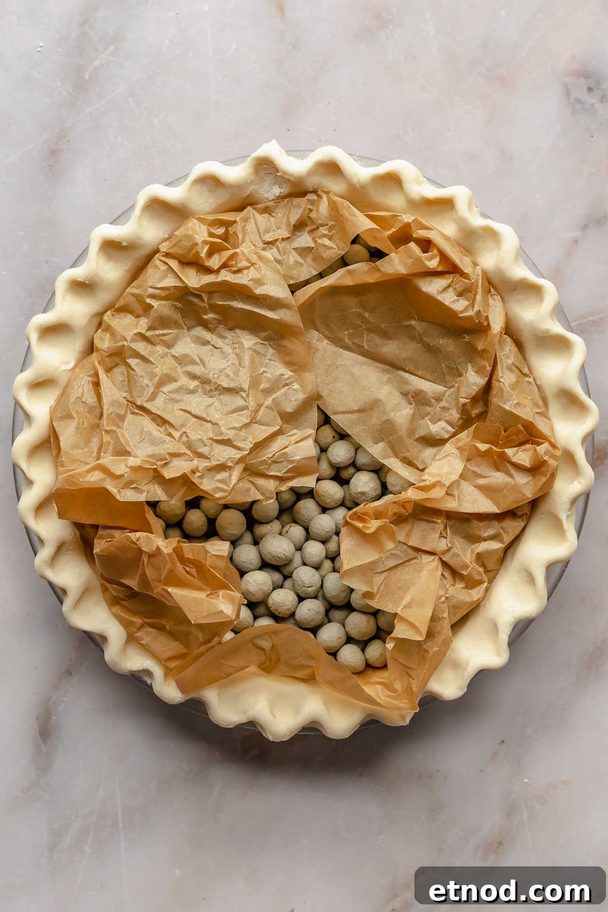 Pie crust filled with parchment paper and pie weights.