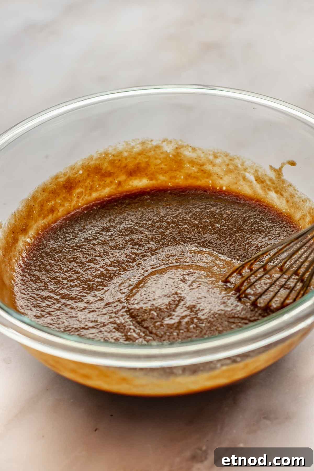A whisk in a bowl with filling ingredients.
