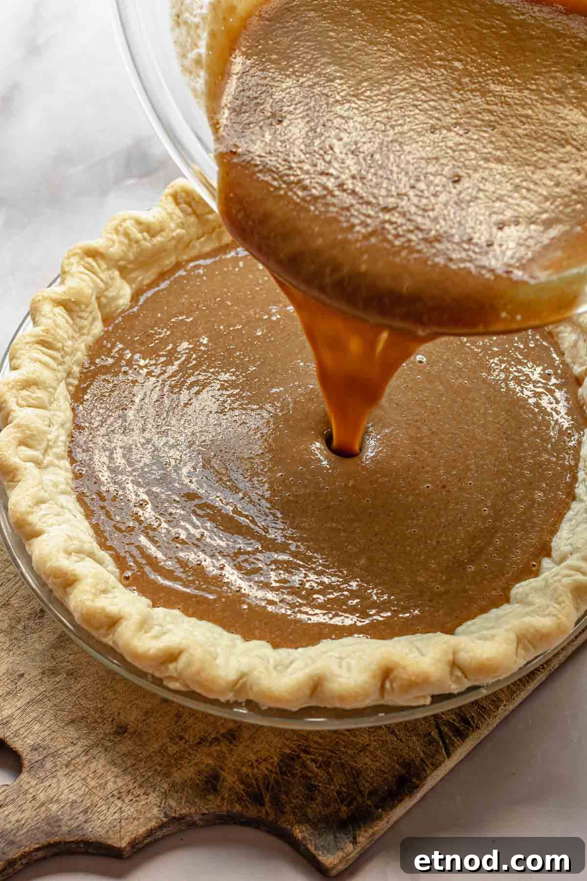 Apple butter pie filling pouring into a pie crust.