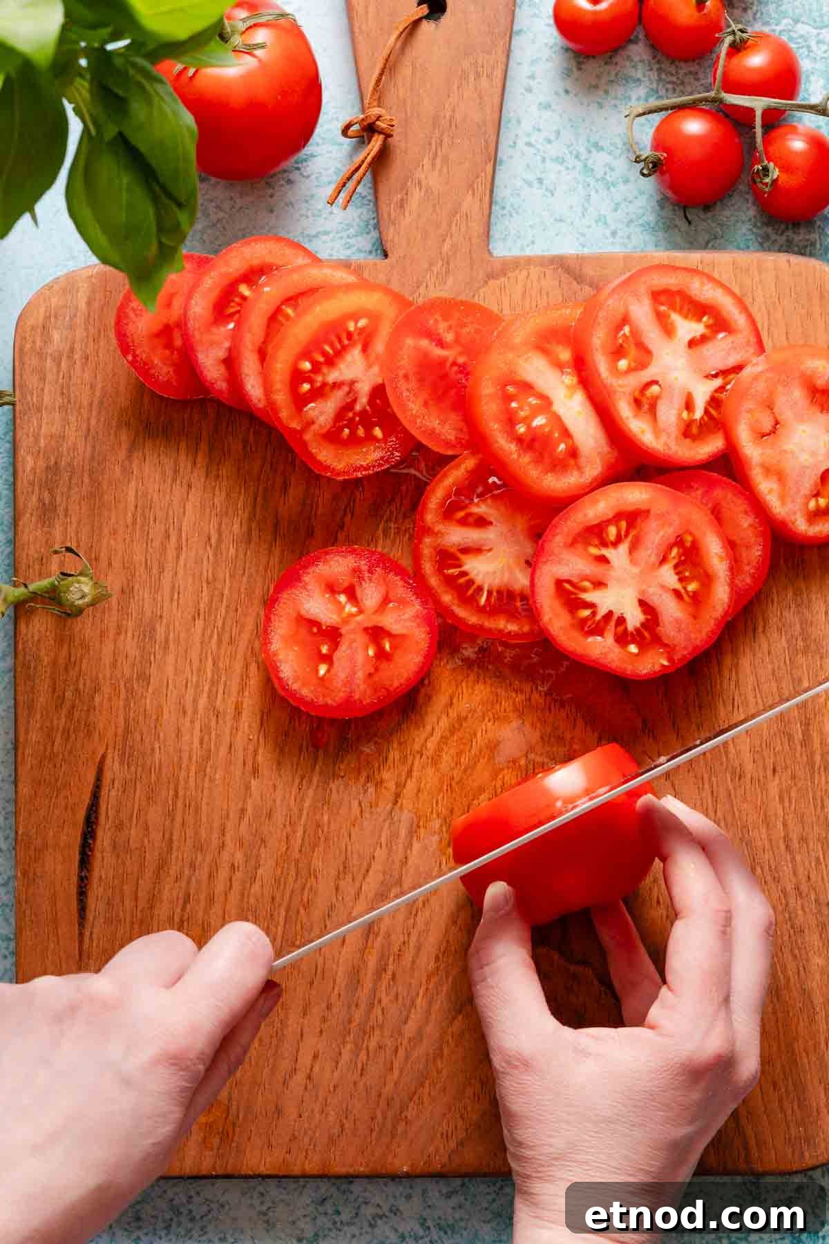 Creamy Burrata Caprese Salad with Heirloom Tomatoes 4 tomatoes being sliced on wooden cutting board.