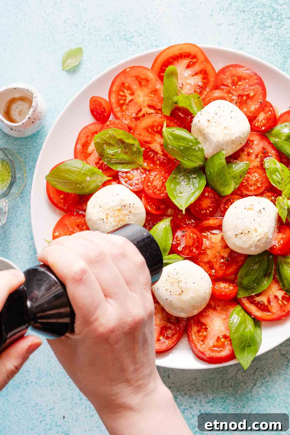 Creamy Burrata Caprese Salad with Heirloom Tomatoes 9 black pepper being ground overtop caprese burrata salad.