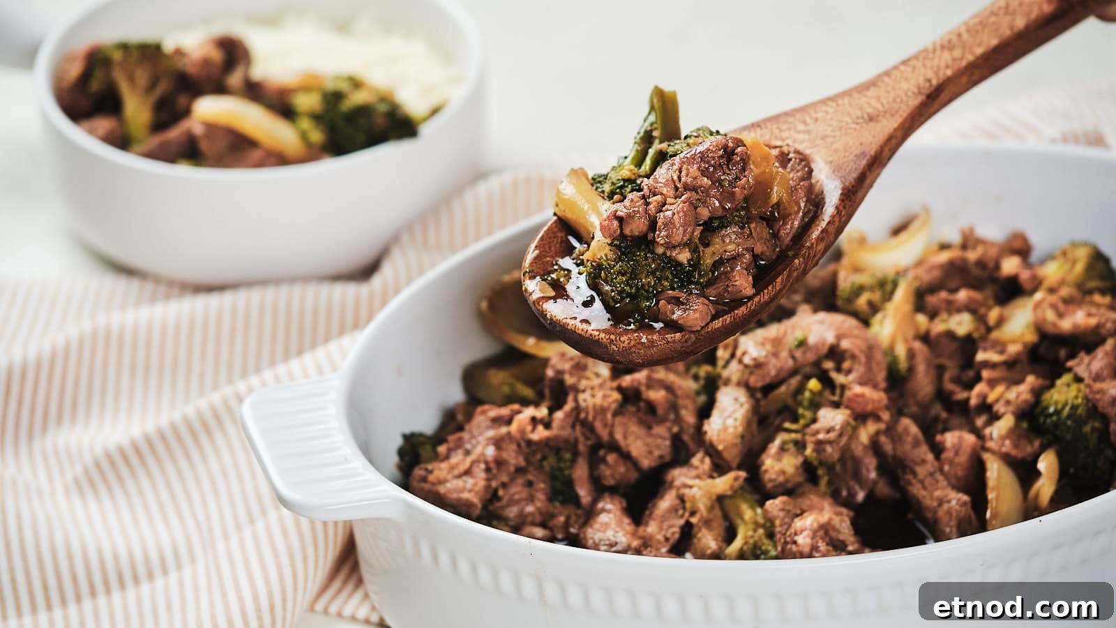 Slow cooker beef and broccoli with onion in brown bowl.