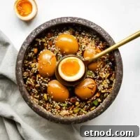 Mayak Eggs Recipe: Korean Soy-Marinated Soft-Boiled Eggs 13 Mayak eggs in a ceramic bowl with one egg sliced in half to show the jammy egg centre.
