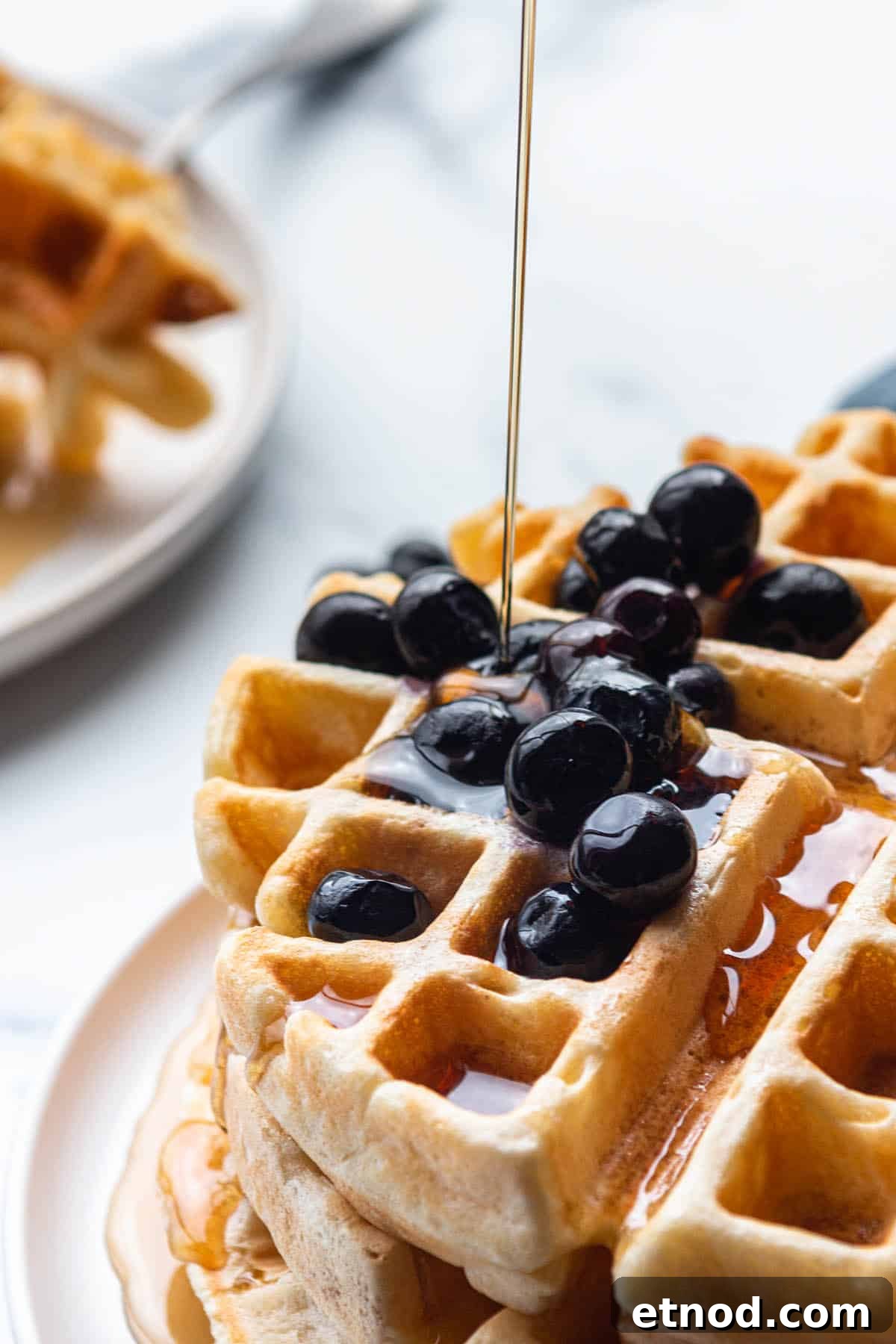 Crispy Sourdough Discard Waffles You’ll Want for Breakfast 2 A stack of waffles with blueberries on top and syrup being poured on.
