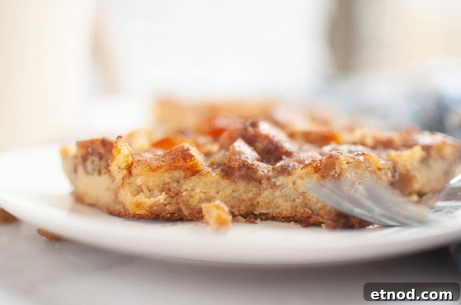 21 Quirky-Looking Desserts That Disappear First at Parties 18 A close-up of a partially eaten piece of Cinnamon Roll Casserole on a white plate, with a fork resting beside it.