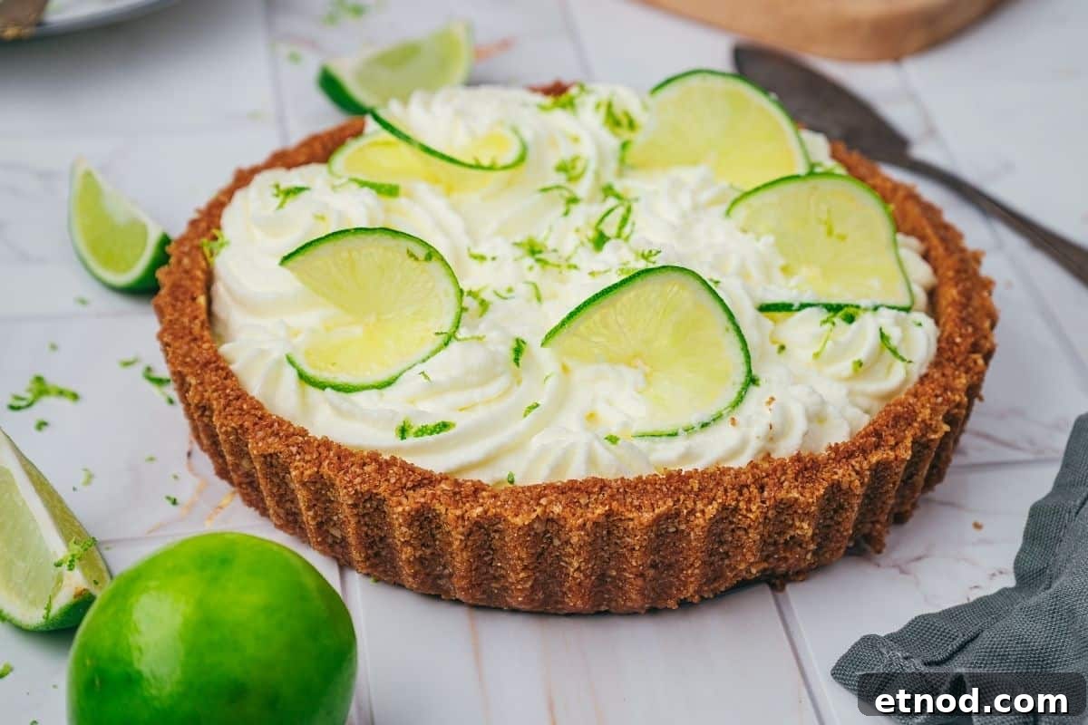 21 Quirky-Looking Desserts That Disappear First at Parties 20 A key lime pie with a graham cracker crust, topped with whipped cream and lime slices, sits on a marble surface with lime wedges nearby.