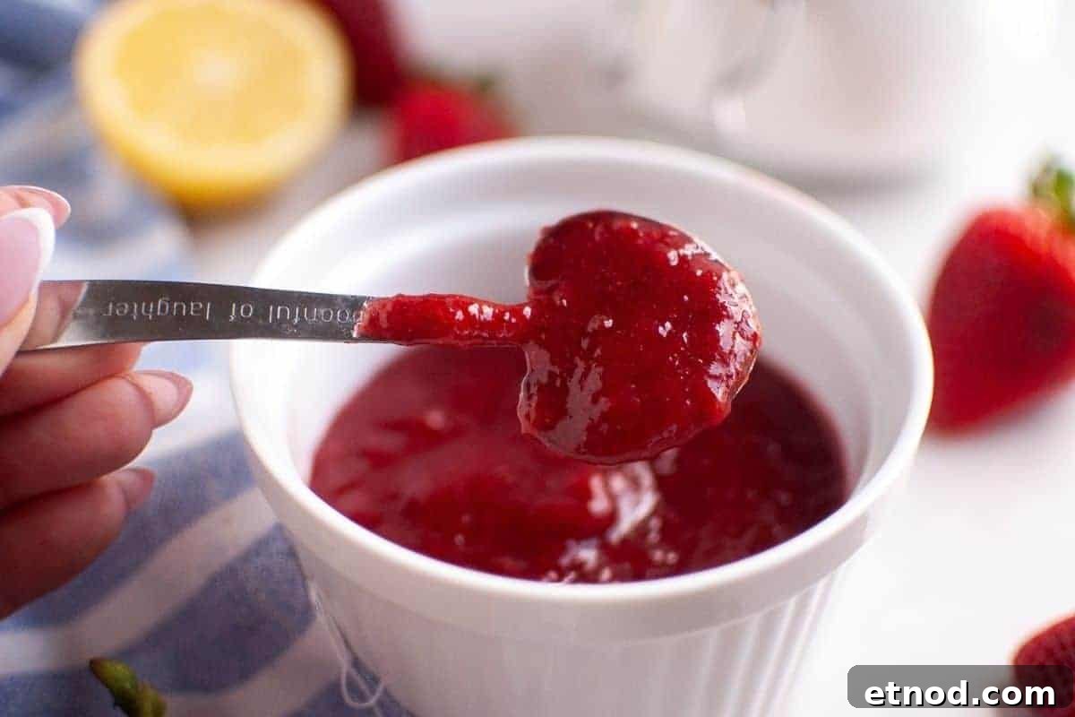 21 Quirky-Looking Desserts That Disappear First at Parties 22 A hand holds a heart-shaped spoon filled with vibrant red strawberry puree above a white ramekin containing more puree, with fresh fruit and a lemon in the background.