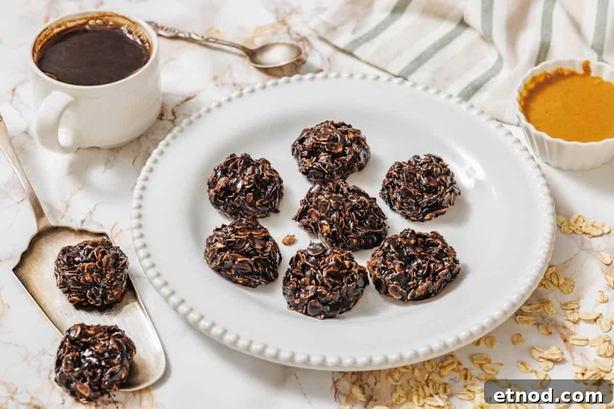 21 Quirky-Looking Desserts That Disappear First at Parties 10 A white plate with seven Peanut Butter No-Bake Cookies on a marble surface, surrounded by a cup of coffee, a spoon, a bowl of nut butter, oats, and a striped cloth.