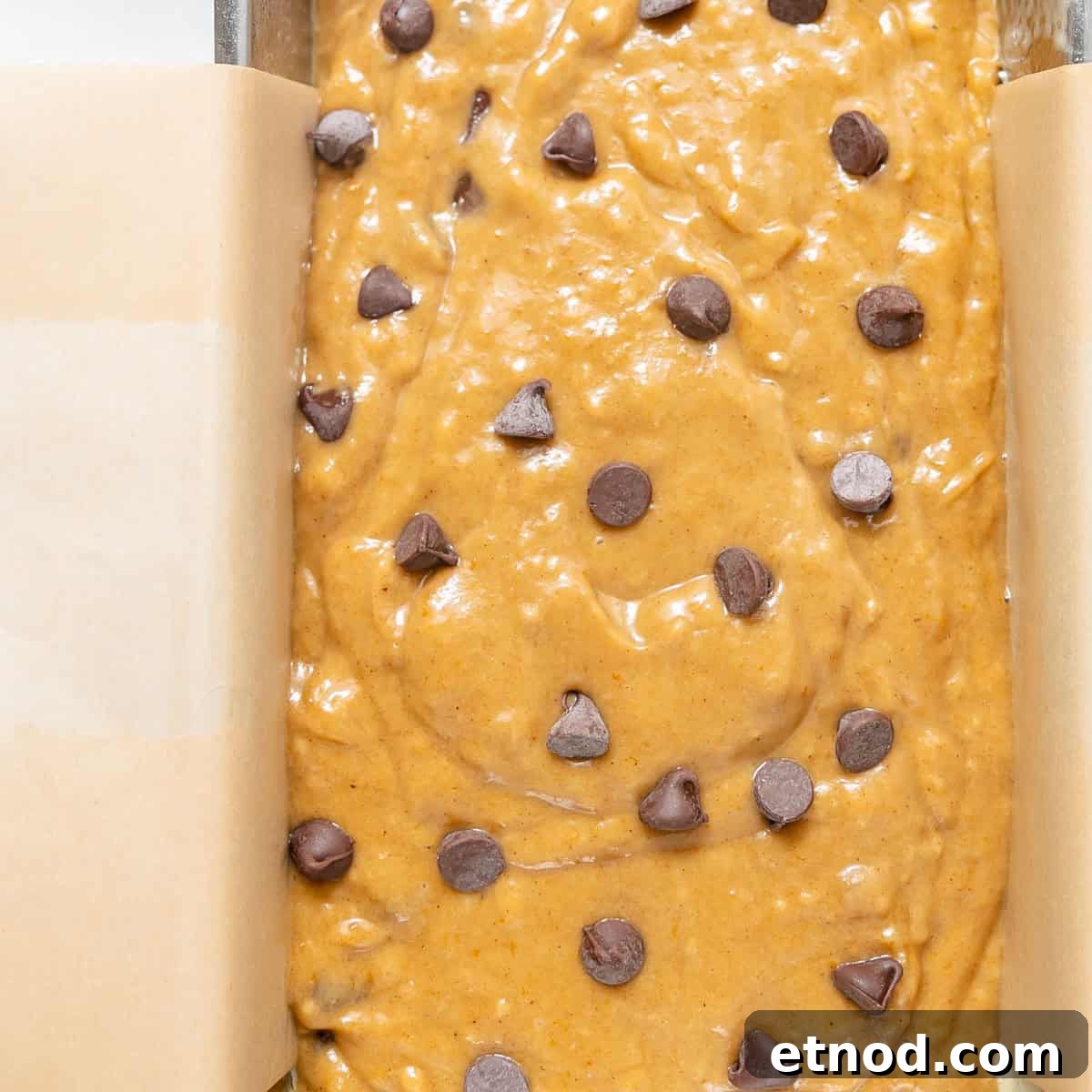 Pumpkin Banana Bread Recipe with Warm Spices and Moist Crumb 7 Batter with chocolate chips spread in a parchment-lined loaf pan, ready to be baked.