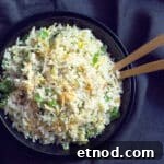 Cilantro Lime Cauliflower Rice with Coconut Flavor 3 A bowl of cauliflower rice sauteed with carrots with 2 serving spoons.