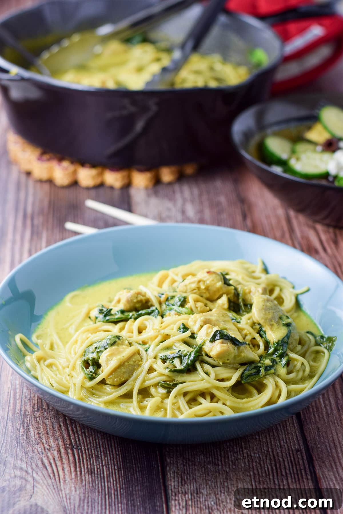 Spicy Chicken Curry Noodles with Coconut and Lime 6 A blue deep dish with noodles, spinach, chicken, and curry sauce - what a pan of the meal behind it