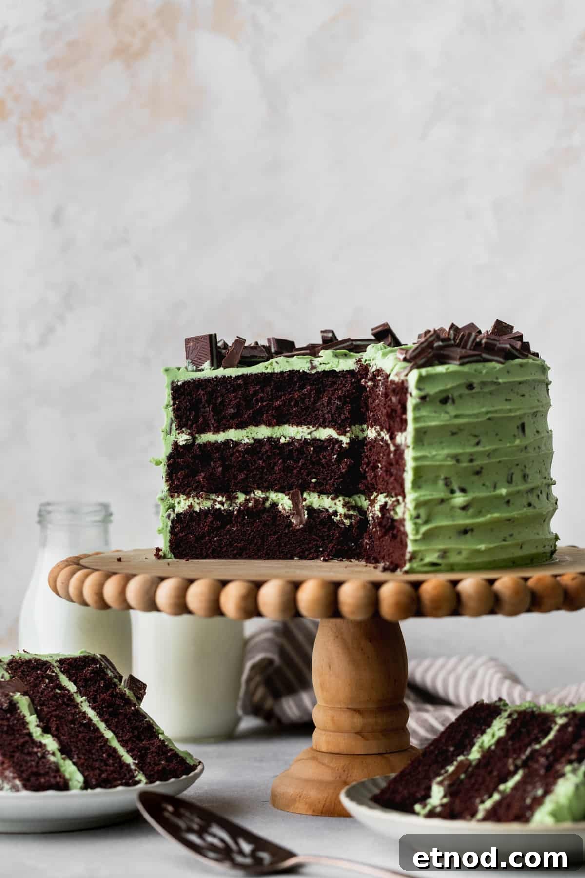 Andes Mint Chocolate Cake Recipe: Rich, Decadent Layer Cake 2 Chocolate mint cake on a cake stand with cake slices around it.